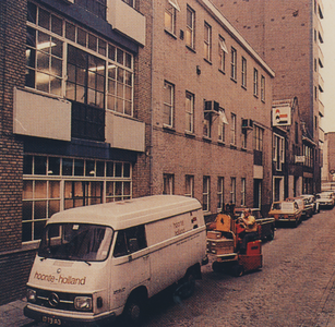 863881 Afbeelding van een bestelauto van drukkerij Hoonte Holland (Willemstraat), die geladen wordt bij een vestiging ...
